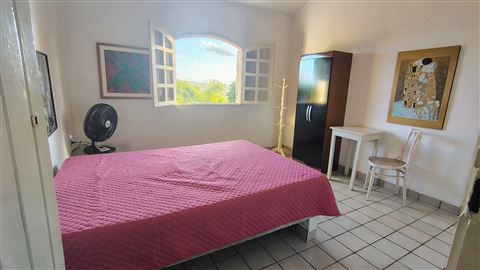 Quarto com cama de casal junto à janela